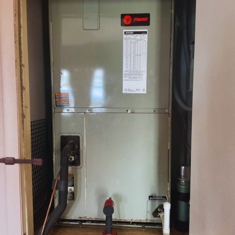Indoor Trane HVAC air handler unit installed in a utility closet with connected refrigerant lines.